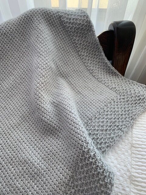 Tunisian crochet projects photo of a grey shawl draped on a chair 
