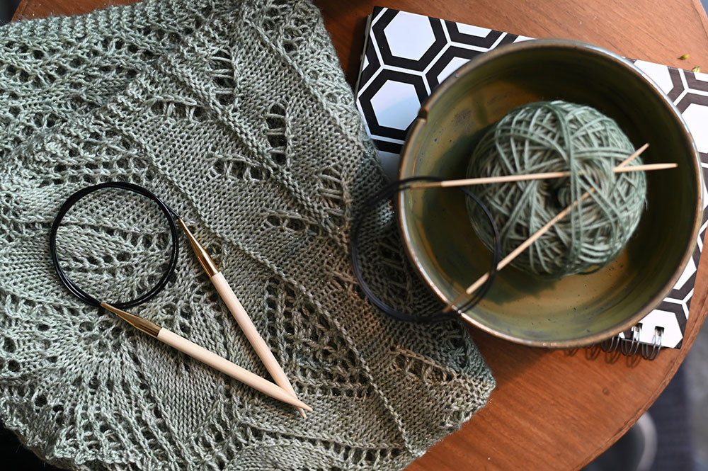 photo of green open knit piece with needles and bowl 