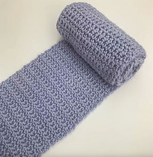 extended single crochet photo of the scarf partly rolled up on a white background 