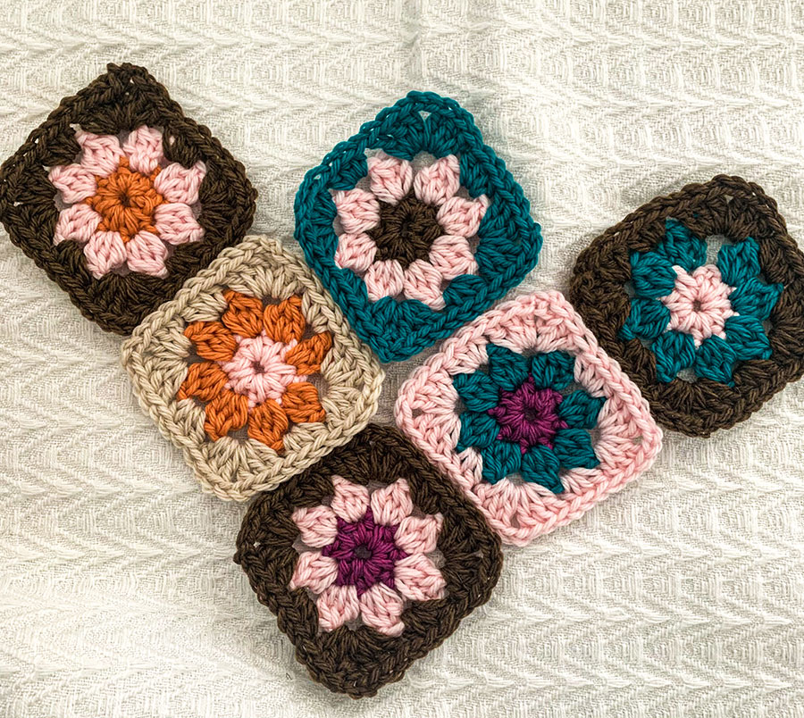 photo of granny squares made with Swish yarn in browns, pinks, teal and orange against a white background. 