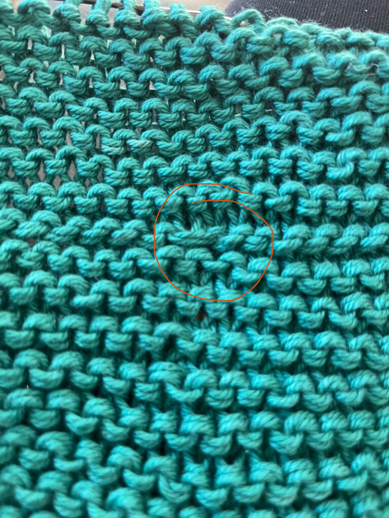 photo of garter stitch fabric in an emerald green with one stitch circled learning to knit photo 