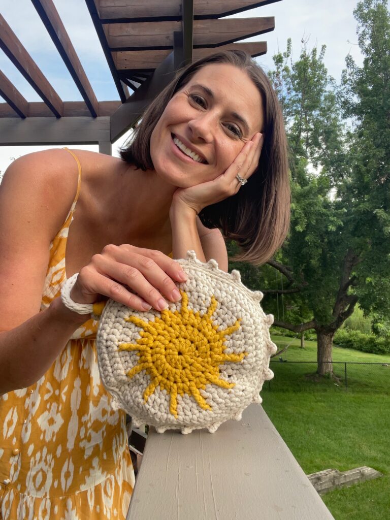 photo of the designer holding her design, a wristlet with sun ray motif 